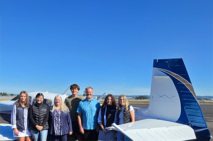 NW Insurance team standing in front of plane with blue sky background